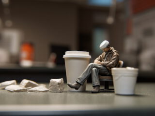 miniatuur persoon neemt pauze tussen koffiebekers